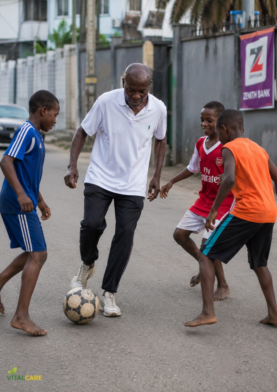 old man playing football with kids